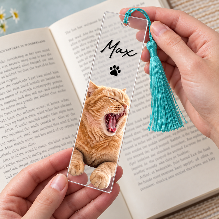 Max cat portrait bookmark with teal tassel held over an open book